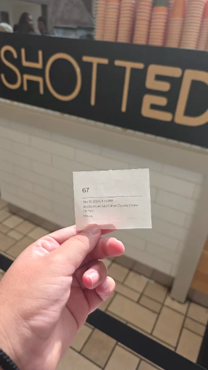 A receipt held up in front of a coffee shop counter.