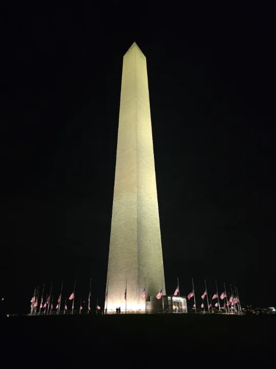 The Washington Monument at night with American flags in front.